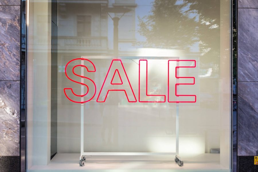 Sale sign in front of an empty clothing rack in shop window