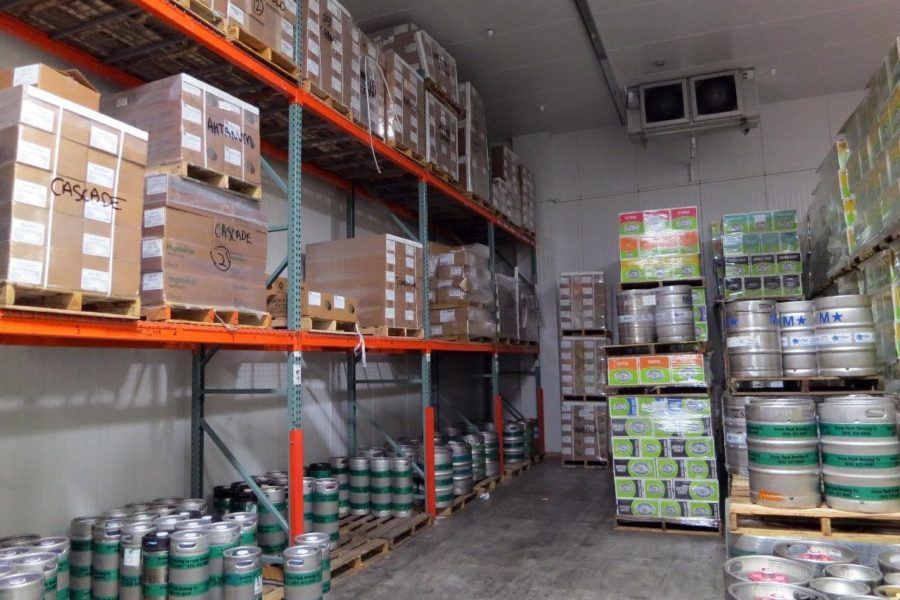 Inside of warehouse showing shelves of pallets, boxes, and barrels