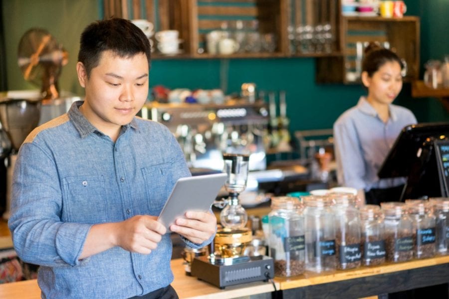 Cafe employee using tablet as personal organizer to add new orders.