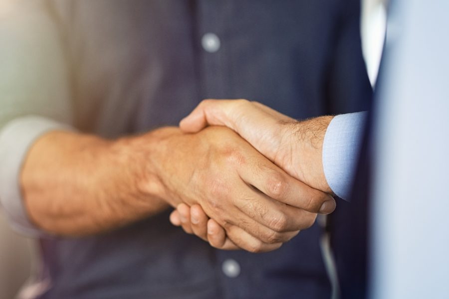 Business partners settling debts with handshake at office