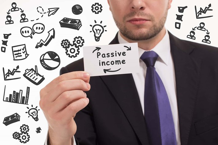Man holding small card reading ‘passive income’ surrounded by business growth graphics