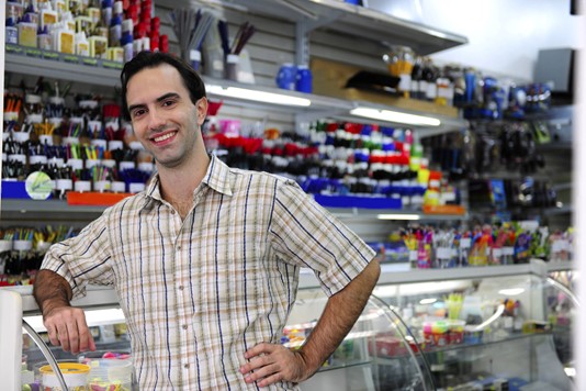 Small business owner stands in front of shelves of art supplies