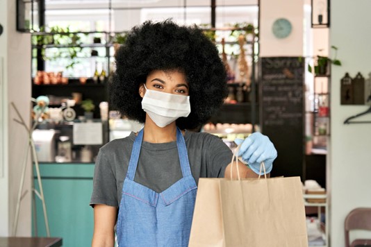 Woman in mask hands over bagged order