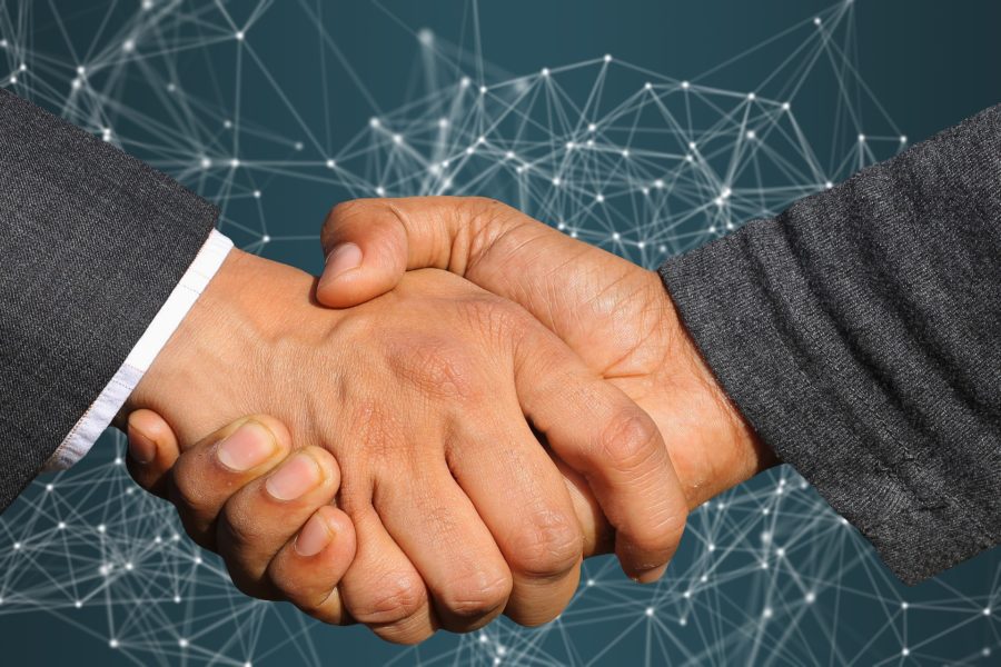 Close up of two people shaking hands against a generic background