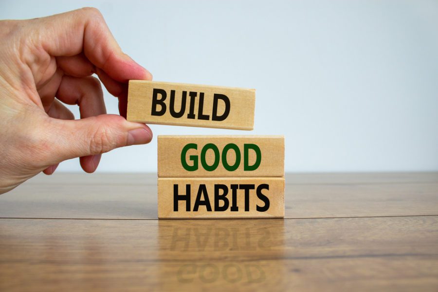 Build good habits symbol. Wooden blocks with words 'build good habits'. Male hand. Beautiful wooden table, white background, copy space.